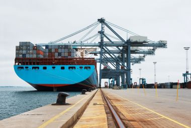 A massive cargo ship moored at the harbour while being loaded with containers